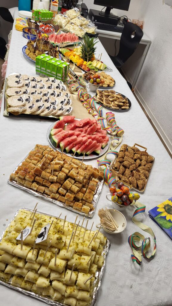 Ein Buffettisch mit vielen arabischen Süßspeisen, Obst und  bunter Dekoration ist abgebildet.