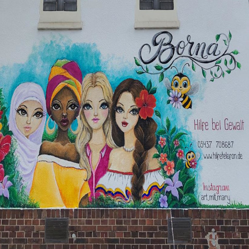 An der Wand eines kleines Häuschen ist ein sehr farbenfrohes Bild gemalt, in dessen Zentrum vier verschiedene Frauen sind, umrahmt von Grün und Blumen. Zudem finden sich verschiedene Schriftzüge, u.a. "Borna", "Hilfe bei Gewalt" oder "wee.hilfetelefon.de".